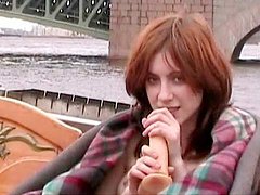 Redhead model is sucking her dildo outdoors